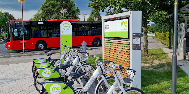 Das Verkehrszeichen fpr Carsharing ist zu sehen. Es beinhaltet ein weißes großes P, das auf einem blauen Verkehrszeichen zu sehen ist, darunter befindet sich ein weiteres Verkehrszeichen, das ein Auto enthält, daneben sind 4 Personen abgebildet, die das Sharing symbolisieren.