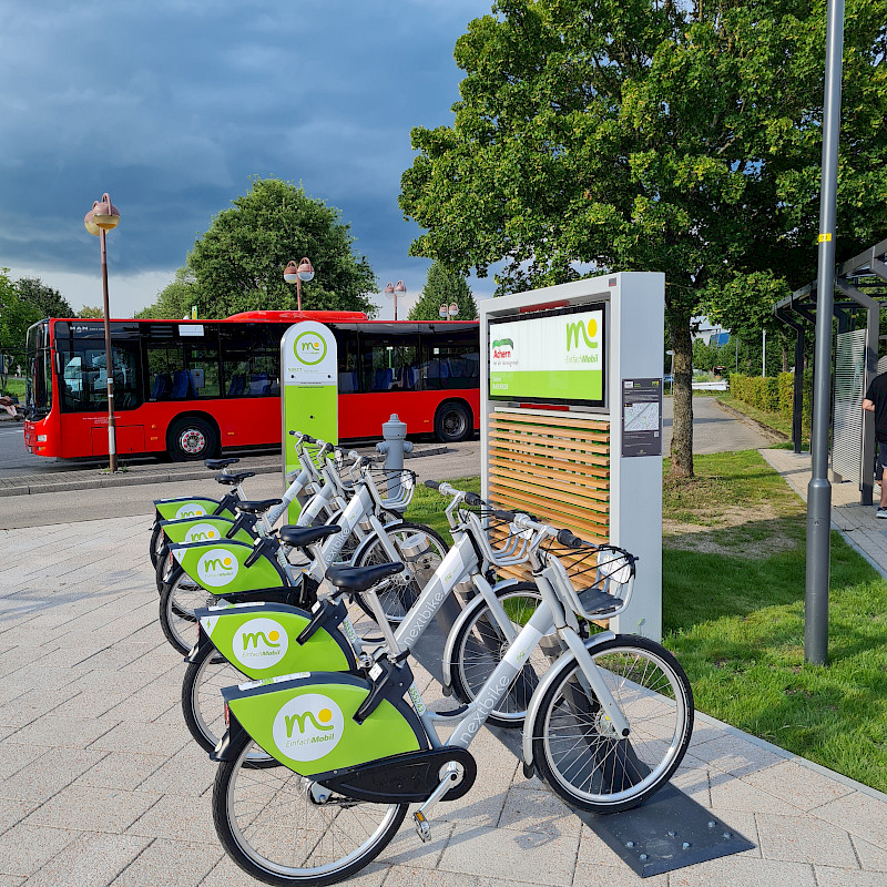 Das Verkehrszeichen fpr Carsharing ist zu sehen. Es beinhaltet ein weißes großes P, das auf einem blauen Verkehrszeichen zu sehen ist, darunter befindet sich ein weiteres Verkehrszeichen, das ein Auto enthält, daneben sind 4 Personen abgebildet, die das Sharing symbolisieren.