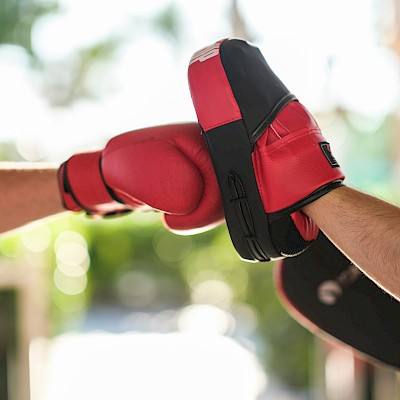 Das Bild zeigt einen roten Boxhandschuh, der gegen eine Handpratze schlägt. Er steht symbolisch für die Konflikte, in denen es in dieser Session geht.