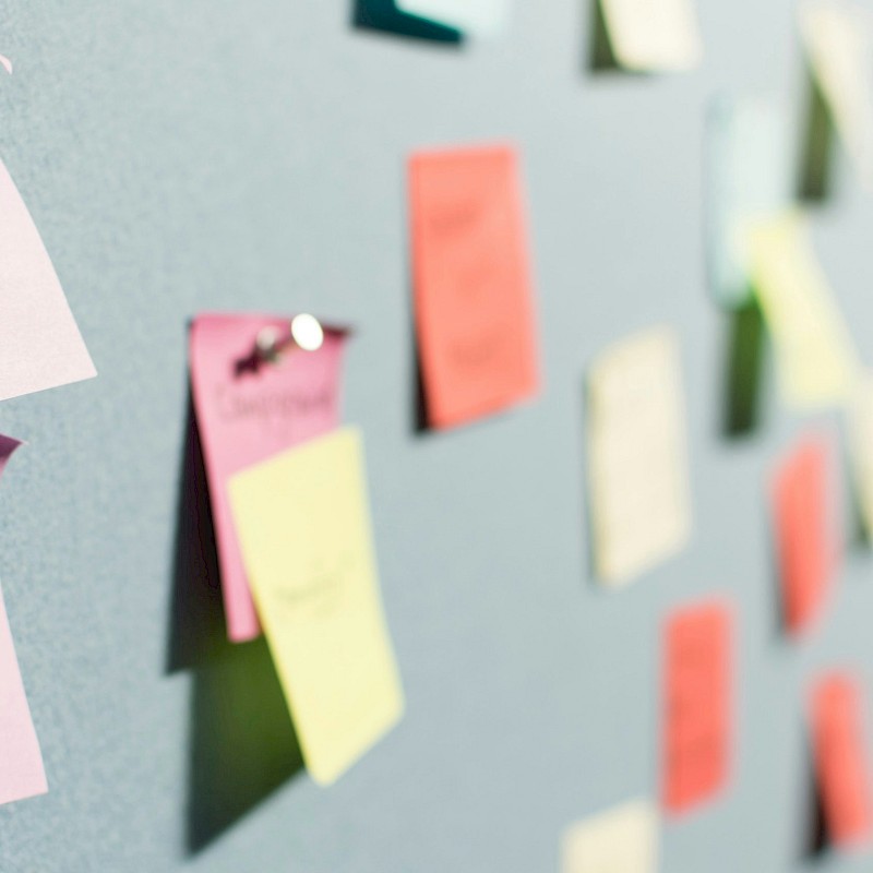 Auf dem Bild sind bunte Post-Its zu sehen, die an Stellwänden sind.