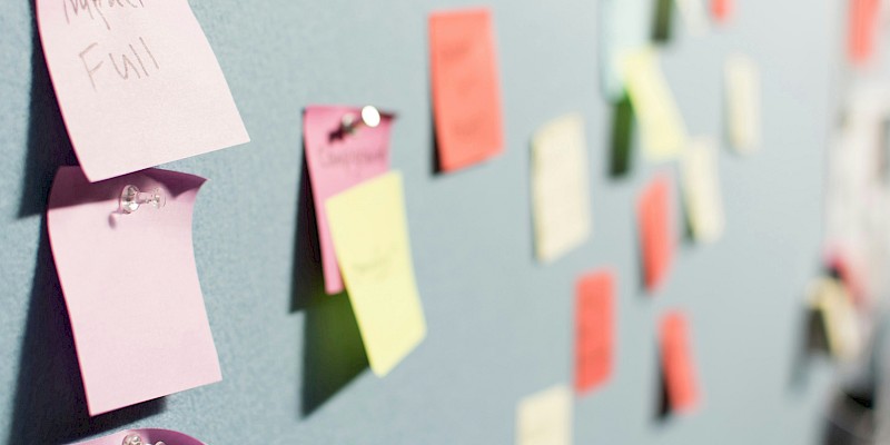Auf dem Bild sind bunte Post-Its zu sehen, die an Stellwänden sind.