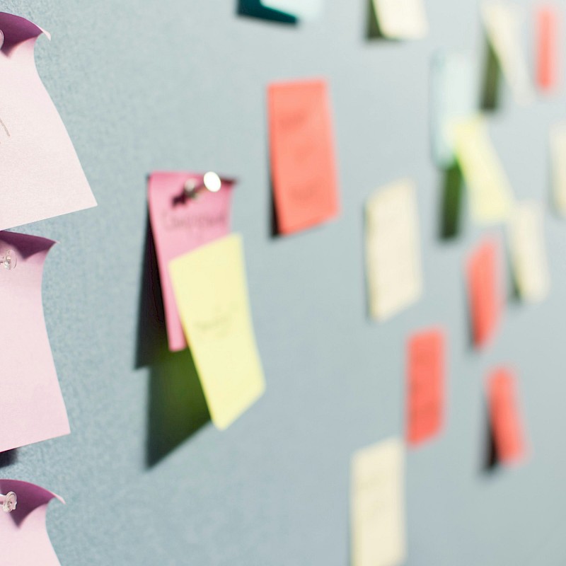 Auf dem Bild sind bunte Post-Its zu sehen, die an Stellwänden sind.