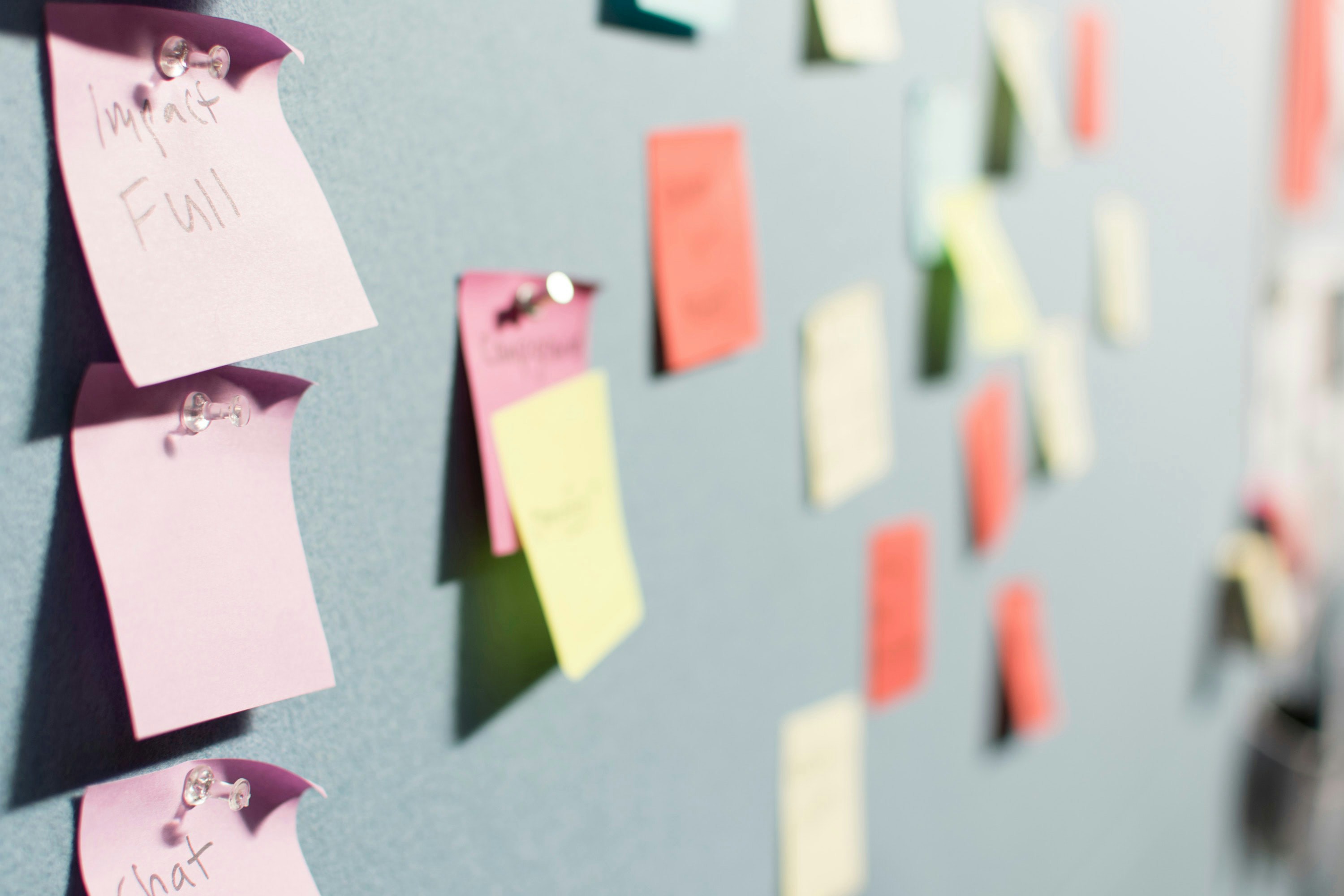 Auf dem Bild sind bunte Post-Its zu sehen, die an Stellwänden sind.