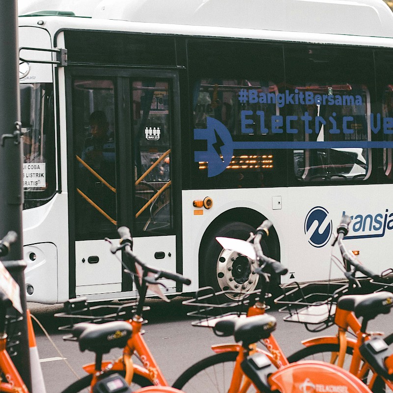 Auf dem Bild ist ein Bus zu sehen, vor dem Bus sind mehrere Leihfahrräder zu sehen.