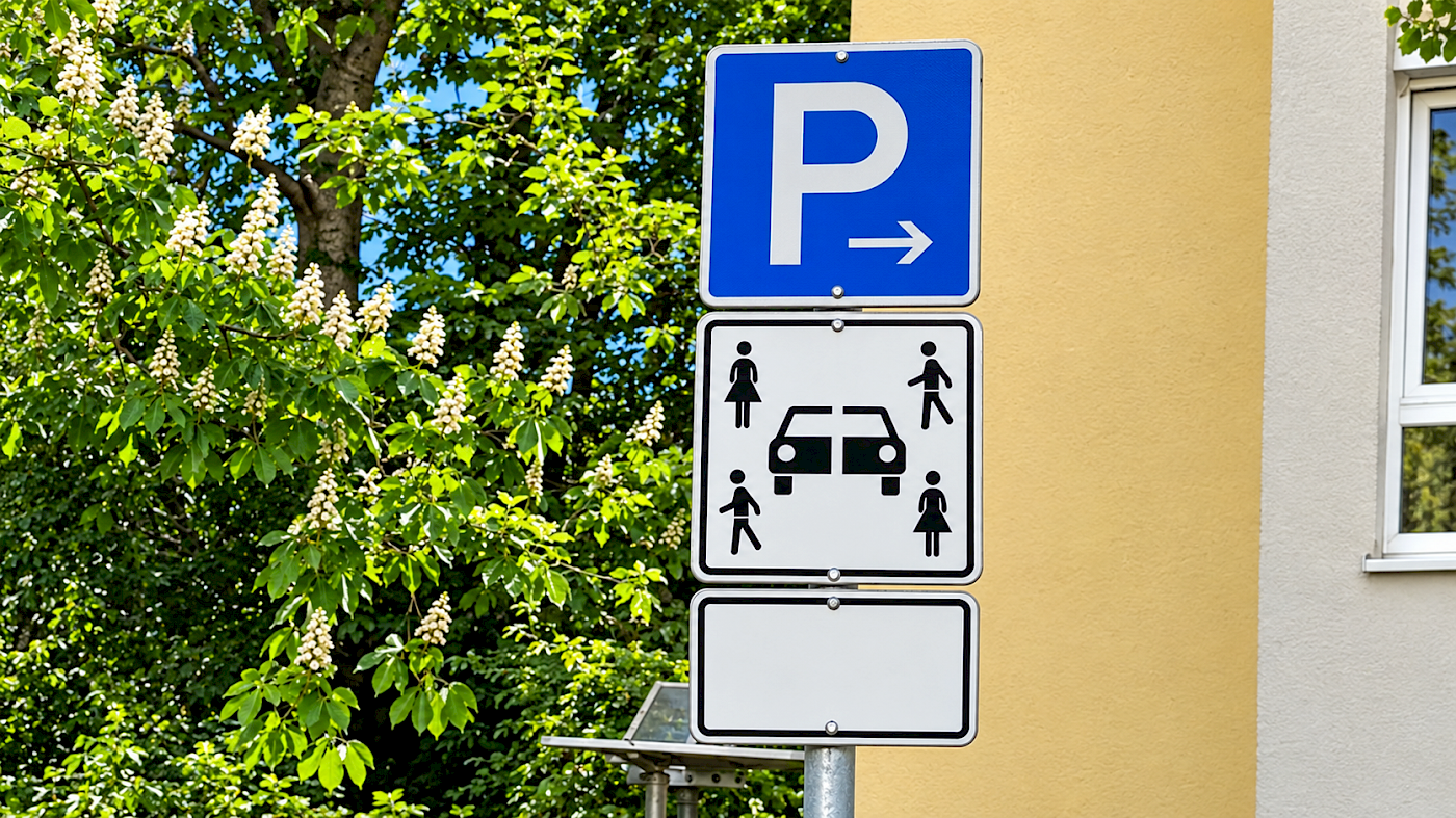 Auf dem Bild ist ein Verkehrsschild, das Carsharing anzeigt zu sehen. Das Verkehrsschild zeigt unter dem Parkenschild vier Personen (zwei männliche und zwei weibliche Piktogramme) und ein durchtrenntes Fahrzeug. Das Zeichen weist klar darauf hin, dass dieser Parkplatz Carsharing-Fahrzeugen vorbehalten ist.